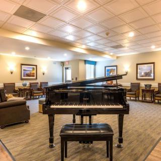 A grand piano in a spacious lounge with comfortable seating and warm lighting.