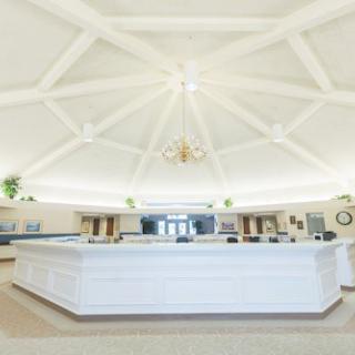 A spacious interior with a central reception desk and intricate ceiling design.