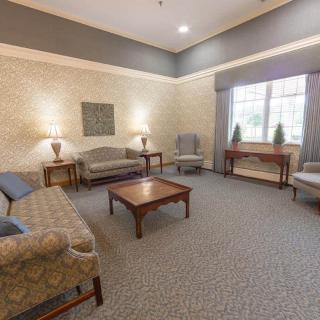 A cozy living room with sofas and a coffee table, softly illuminated by lamps.