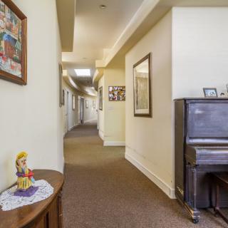 A hallway with a piano and framed wall art.