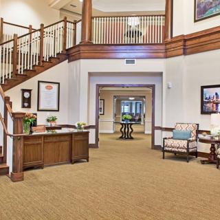 A spacious lobby with a reception desk, seating area, and wooden staircase.