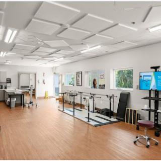 A well-equipped rehabilitation therapy room with exercise equipment and ample natural light.