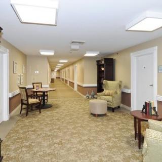 A well-lit corridor with comfortable seating and tables along the walls.
