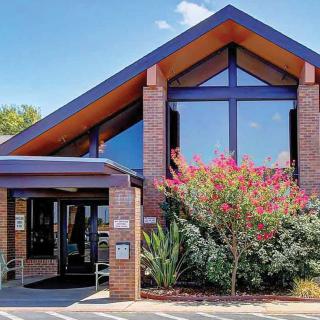 A modern brick building with large windows and well-maintained landscaping at the entrance.