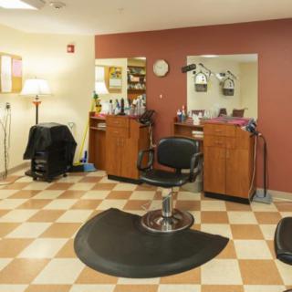 An empty hair salon with a barber chair, mirrors, and a checkerboard floor.