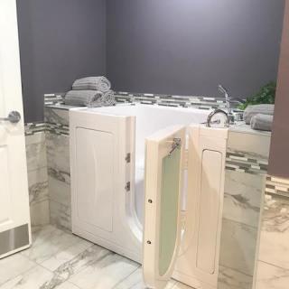 A modern bathroom featuring an accessible walk-in bathtub with open door.