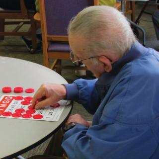 An elderly man sitting at a table playing bingo.
