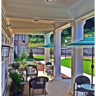 A cozy outdoor patio with seating, tables, and umbrellas overlooking a garden.