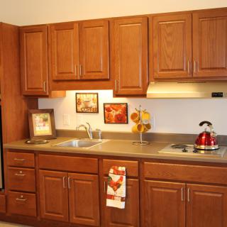A cozy kitchen with wooden cabinets, a sink, stove, and decorative elements.