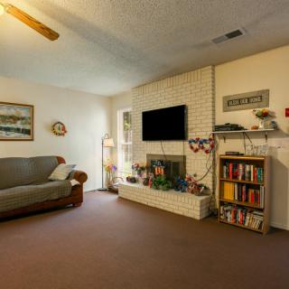 A cozy living room with a sofa, bookshelf, and a mounted television above the fireplace.
