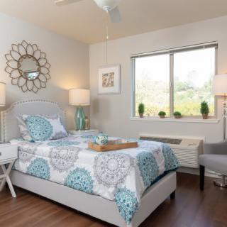 A modern bedroom with stylish decor including a bed with patterned bedding, decorative lamps, and a wall mirror.