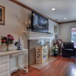 A cozy living room featuring a fireplace with a television mounted above it, hardwood flooring, and comfortable seating.
