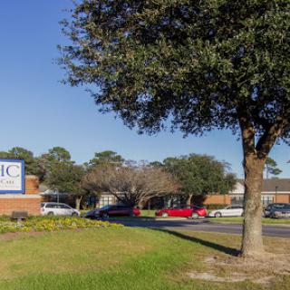 A view of a building with signage, surrounded by greenery and trees under a clear blue sky.
