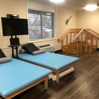 A cozy room equipped with blue mattresses, a television setup, and wooden stairs.