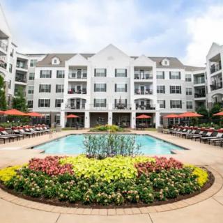 A view of a residential building with a landscaped pool area and vibrant flower beds.