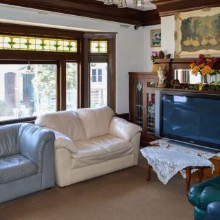 A cozy living room featuring sofas, a large television, and decorative elements with ample natural light from the windows.