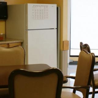 A kitchen area with a refrigerator, chairs, and table.