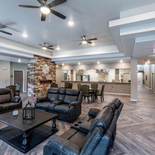 A spacious modern living room with leather seating, a stone fireplace, and an open floor plan.