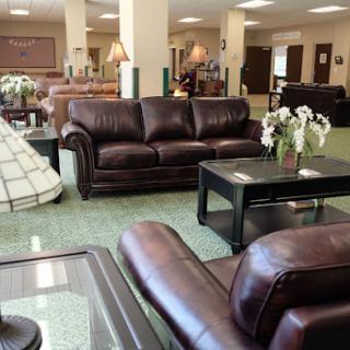 A cozy living room setting featuring a brown leather sofa, a glass coffee table, and decorative flowers.
