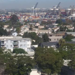 A panoramic view of a residential area, with distant industrial cranes and a harbor in the background.