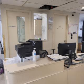 A view of an office reception area featuring a desk with a printer and computer.