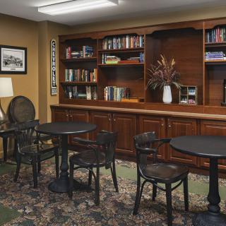 A cozy library interior with bookshelves, round tables, and chairs arranged for reading.