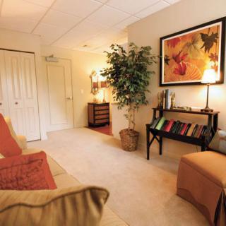 A cozy living room with comfortable seating, a potted plant, and vibrant artwork on the wall.