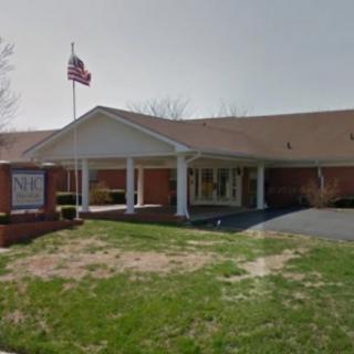 A brick building with an American flag and a lawn at the front.