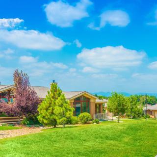 A picturesque house surrounded by lush greenery and a clear blue sky.
