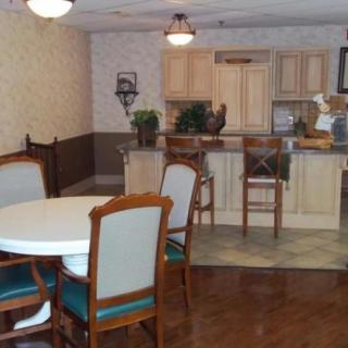 A cozy kitchen and dining area featuring a round table with chairs, bar stools, and light-colored cabinets.