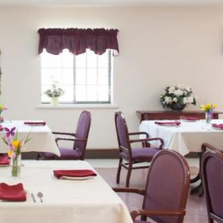A cozy dining room with neatly arranged tables and chairs, adorned with flowers and elegant table settings.