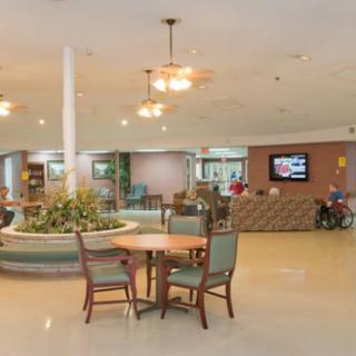 A spacious lobby with seating and a reception desk, featuring indoor plants and ambient lighting.