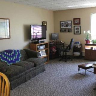 A cozy living room with a sofa, television, and a small desk setup.