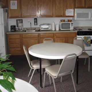 A kitchen area with a round table and chairs, featuring wooden cabinets and standard appliances.