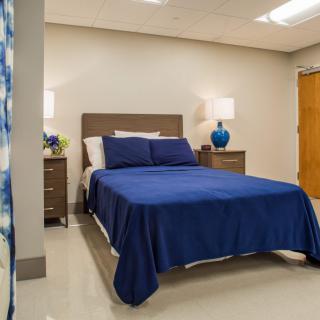 A modern bedroom with a blue-themed bedding and matching lamps.