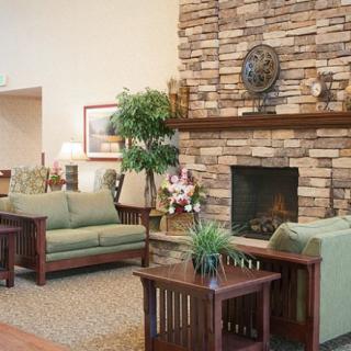 A cozy living room featuring a stone fireplace, comfortable sofas, and lush greenery.