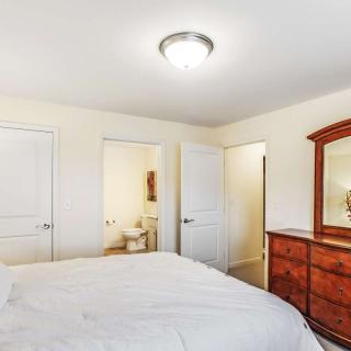 A cozy bedroom featuring a bed, dresser with mirror, and warm lighting.