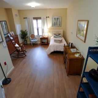 A cozy bedroom with wood flooring, a single bed, and classic decor.