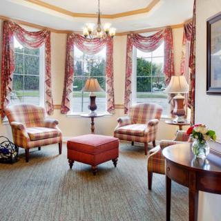 A cozy living room with plaid chairs, red drapes, and a centrally placed table.