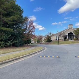 A quiet street leading to a building under a blue sky with scattered clouds.