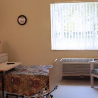 A simple hospital room with a bed, chair, and window.
