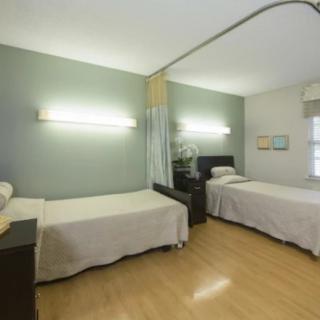 A hospital room with two neatly arranged beds and dividing curtains.