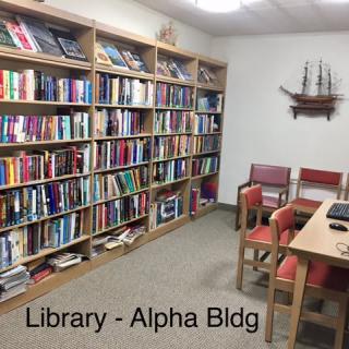 A cozy library corner with bookshelves and a small seating area in the Alpha Building.