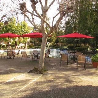 Outdoor seating area with red umbrellas and a pool.