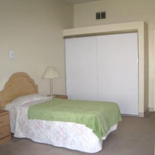 A minimalist bedroom with a single bed and a closet.