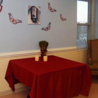 A room with a table covered in a red tablecloth, adorned with candles and decorations on the wall.
