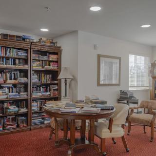 A cozy library reading area with bookshelves, a round table, and chairs.