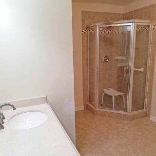 A bathroom with a corner shower and a sink countertop.