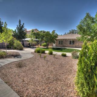 A serene garden pathway surrounded by lush greenery and a well-maintained lawn.