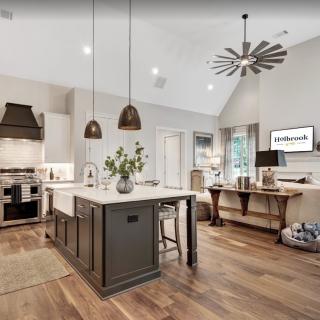 A modern kitchen with an island, pendant lights, and wood flooring.